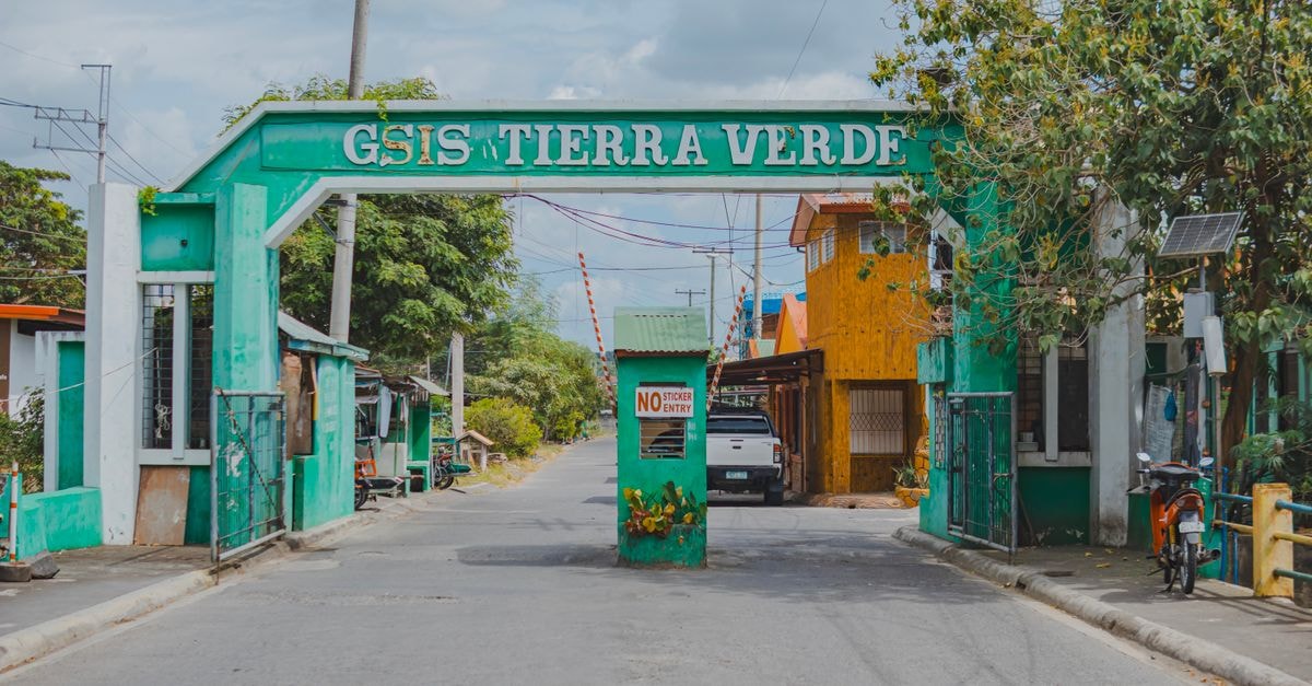 Urban entrance gate of GSIS Tierra Verde with vibrant greenery and a clear sky.