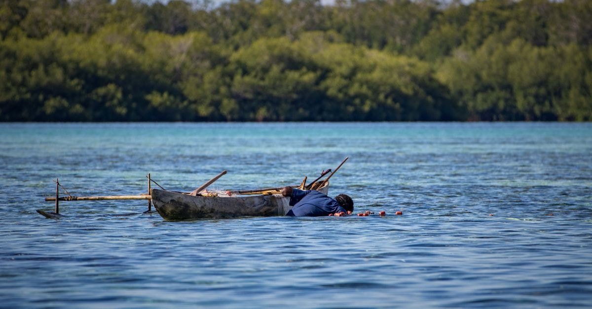 Man in a canoe on pristine waters, traditional fishing in Papua New Guinea.