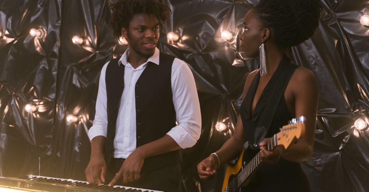 Masego's "Fix Your Face" Album and Odeal's Afrobeats Summer Playlist Highlight R&B Week A male pianist and female guitarist perform together in a stylish indoor setting.