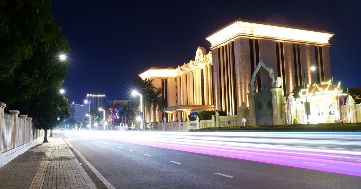 Khamvongsa Hotel, Vientiane — A Family-Run Stay in the Old Town Vibrant urban street at night showcasing illuminated buildings and dynamic light trails.
