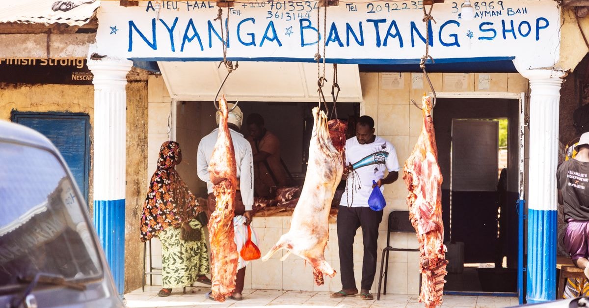 Traditional butcher shop with hanging meat display in a village setting, capturing local commerce.