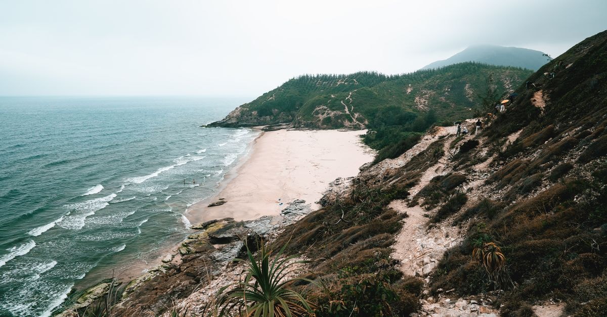 Slow Coast Escape: A Travel Guide to Fangchenggang A beautiful coastal scene featuring a serene sandy beach nestled between lush hills and the vast ocean.