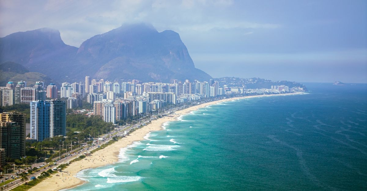 Riale Brisa Barra Hotel, Barra da Tijuca — A Convenient Western Rio Address Stunning aerial view of Barra da Tijuca beach with city's skyline and mountains in Rio de Janeiro, Brazil.