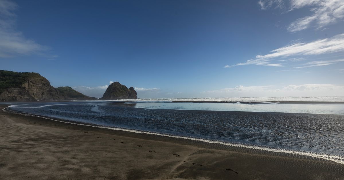 Auckland Travel Guide: Weather, Transit, and Coastal Flavors Beautiful coastal landscape with rocks and ocean under a clear sky.