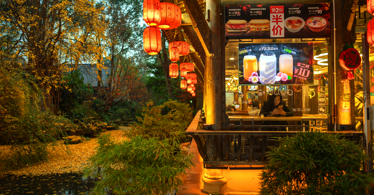 Chengdu Travel Guide: Planning Tips, Costs and Things to Do A cozy Chinese restaurant by the river with red lanterns glowing warmly at night in Chengdu, China.