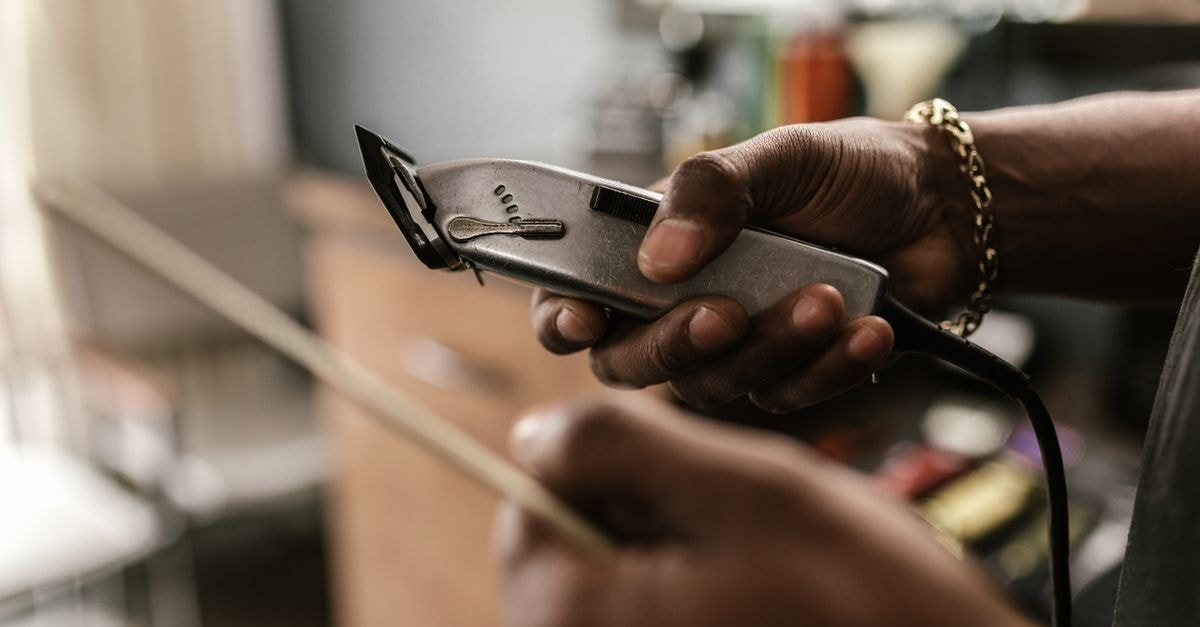 NBA notebook: Clippers-Raptors Leonard deal on hold, Portland weighs $600M Moda Center revamp Close-up of a barber holding clippers in a barbershop, focusing on hands and equipment.