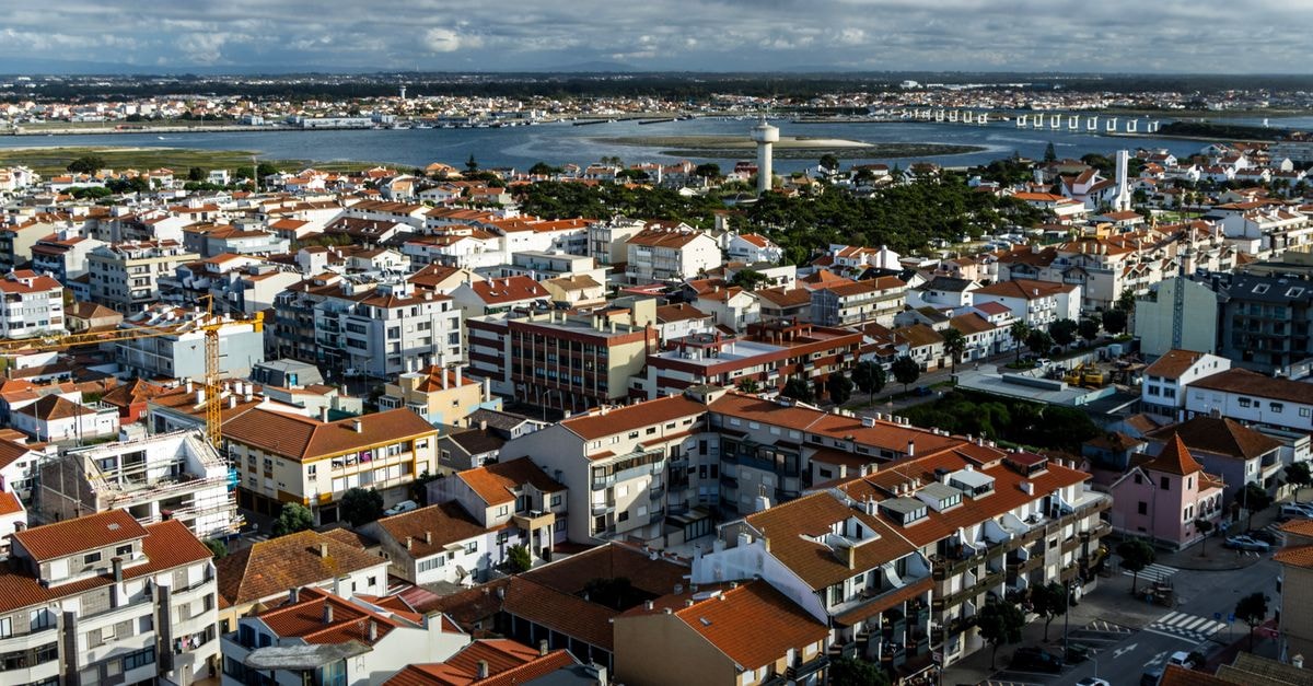 Douro Village in Vila Real — A Hostel in the Historic Heart of Town Aerial view of a picturesque coastal town with red-roofed buildings and a river backdrop.