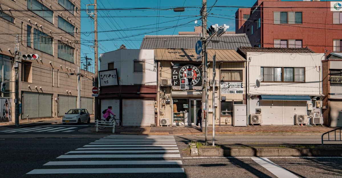Kasugai Travel Guide: Quiet City with Easy Nagoya Access Cyclist traversing a crosswalk in Nagoya, showcasing city life and architecture.