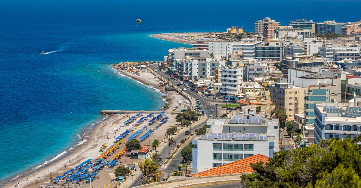 Domus Rodos in Rhodes Old Town: A Platonos Street Stay Stunning aerial view of Rhodes cityscape and coastline, highlighting vibrant beaches and azure waters.
