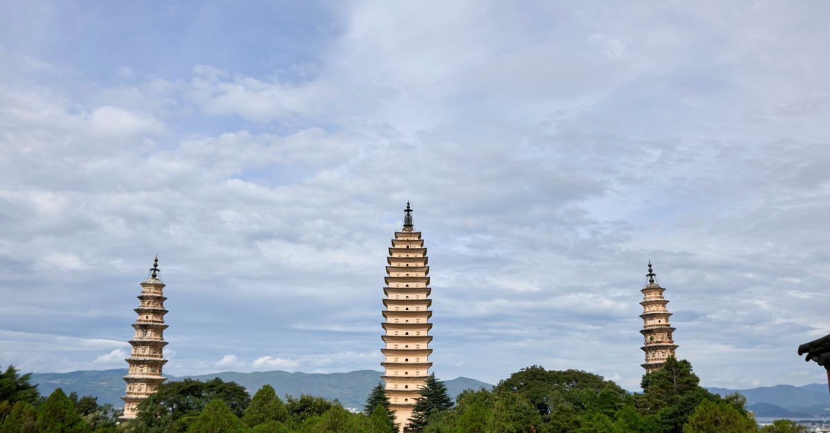 Jinjiang Inn in Dali: A Practical Xiaguan Stop Near Erhai Lake A tranquil view of three ancient pagodas surrounded by lush greenery under a blue sky.