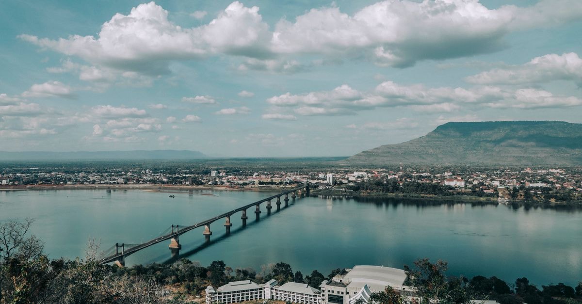 Vientiane Travel Guide: Planning Tips and Things to Do A picturesque bridge spans the Mekong River in a tranquil Laotian landscape.