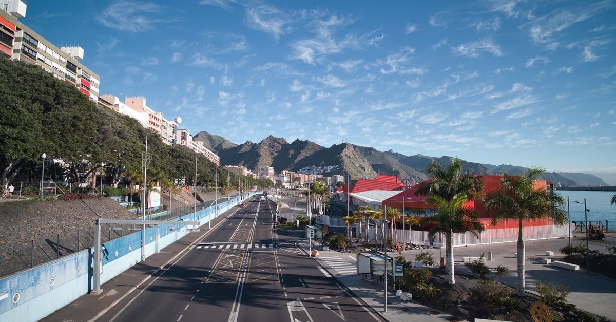 Explore the vibrant cityscape of Santa Cruz de Tenerife featuring colorful architecture and scenic mountains.