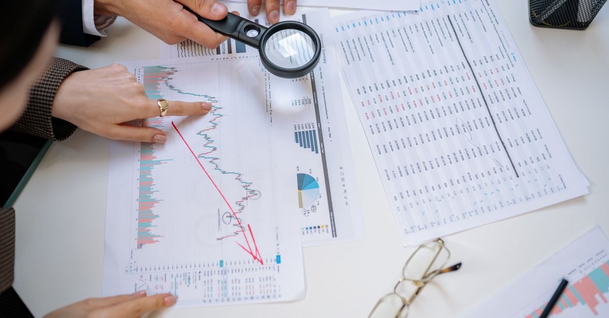 Hedge Funds Open New Positions in Philip Morris International as Q2 13F Filings Surface Business professionals examining financial documents with magnifying glass for detailed analysis.