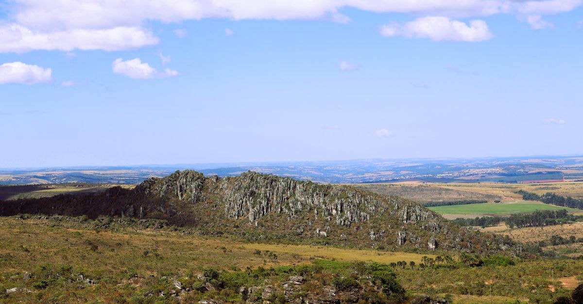 Expansive view of Morro do Cabeludo rock formation in Brazil's summer countryside.