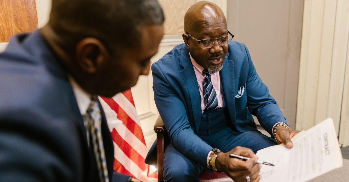Nick Chubb to sign one-day contract with Browns and retire as a Cleveland player Two businessmen reviewing a contract document in an office setting.