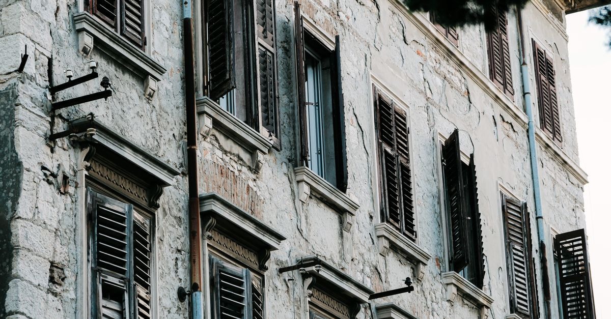 A vintage stone building in Croatia featuring weathered wooden shutters, showcasing historical architecture.