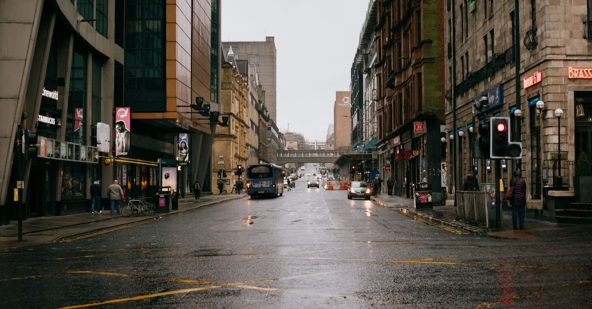 Glasgow Travel Guide: Planning Tips, Costs and Things to Do A rainy day in Glasgow's city center with traffic and pedestrians on wet streets.