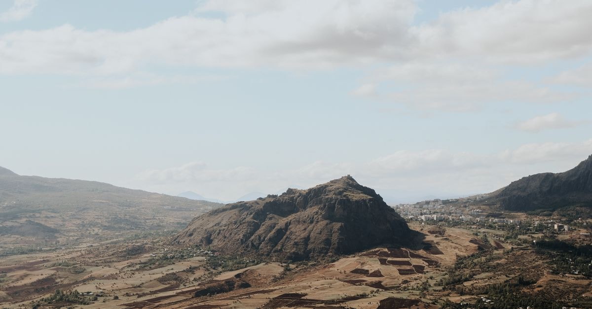 Aerial view of rocky mountain landscape under a clear blue sky with clouds.