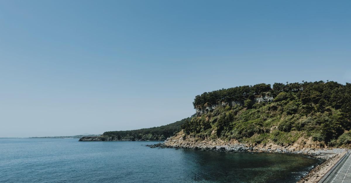 You&I in Jeju City: A City Hall-Area Guesthouse on Gwangyang 8-gil Breathtaking view of Jeju Island's coastline with clear skies and lush greenery.