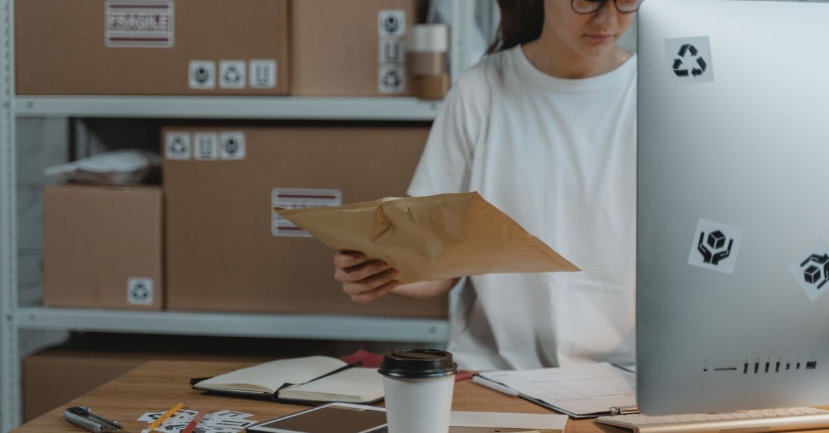 UPS Announces Kate Gutmann's Retirement and Global Operating Model Effective September 1, 2026 Woman sorting parcels at her desk in a logistics office, demonstrating efficient workspace organization.
