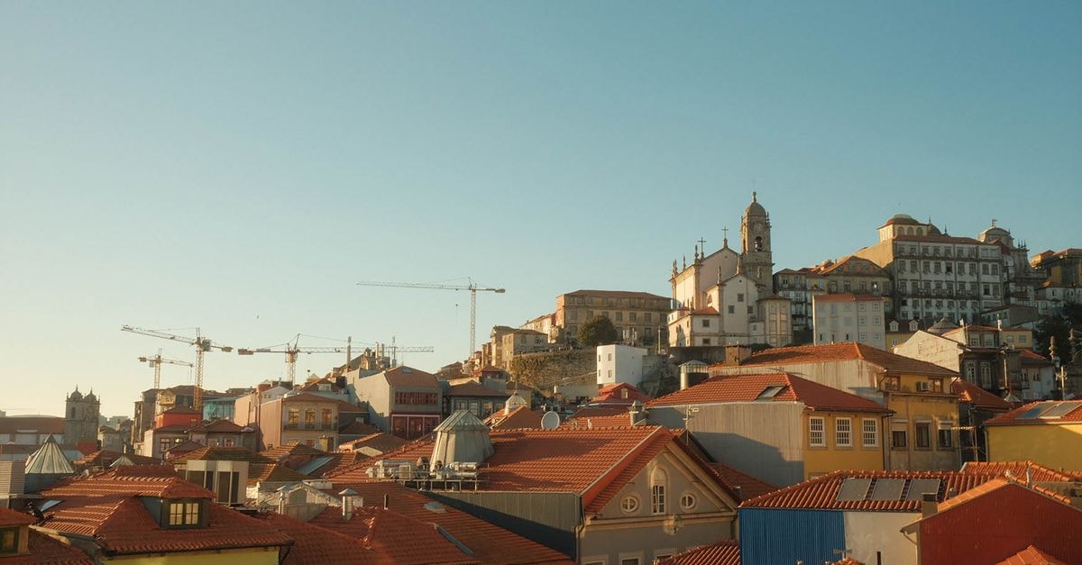 Eurostars Aliados in Porto: A Stay on Avenida dos Aliados Panoramic view of Porto, Portugal with historic rooftops and cranes at sunset.