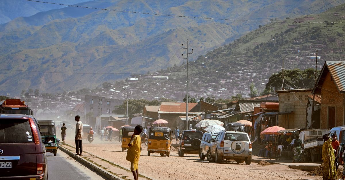 Fianarantsoa travel guide: a slow pause in Madagascar's highland capital A vibrant rural street bustling with people and vehicles against a stunning mountain backdrop.