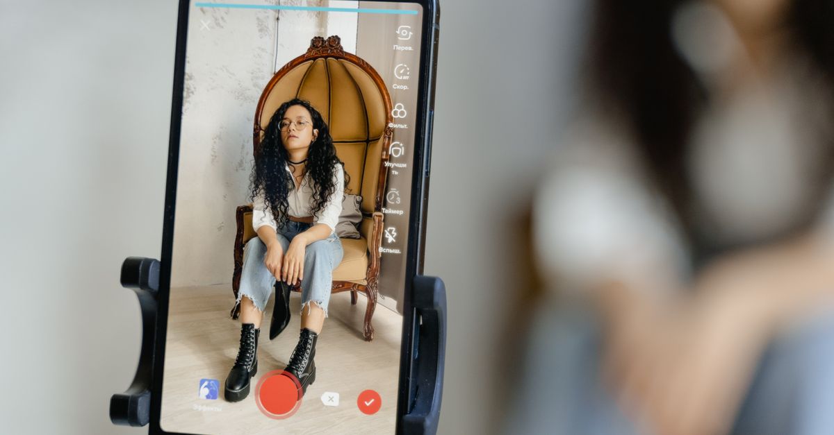 Katy Perry rebukes White House TikTok over unauthorized use of 'Firework' in military strike video A woman sits in a chair recording a video on her smartphone, showcasing modern vlogging techniques.