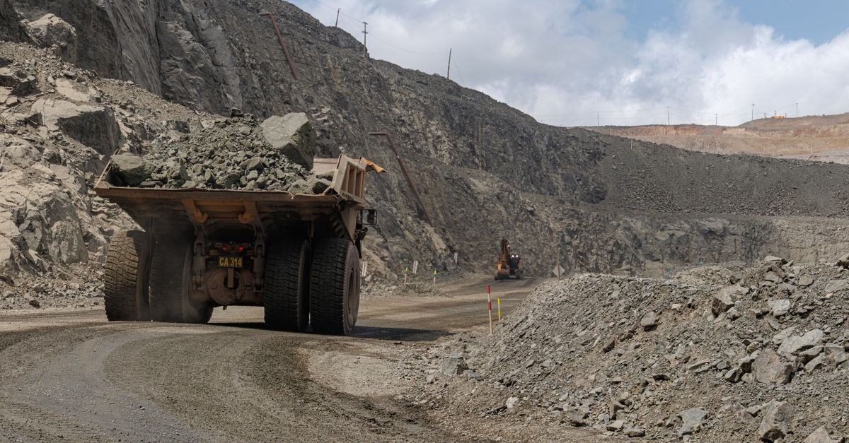 NMDC reports 21% YoY rise in August iron ore output A large mining truck transporting rocks in an open-pit quarry, showcasing industrial machinery.