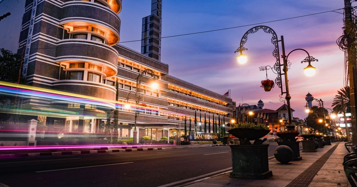 Pekanbaru Travel Guide: Getting Around and Eating Well Art Deco architecture illuminated at twilight in Bandung, Indonesia street scene.