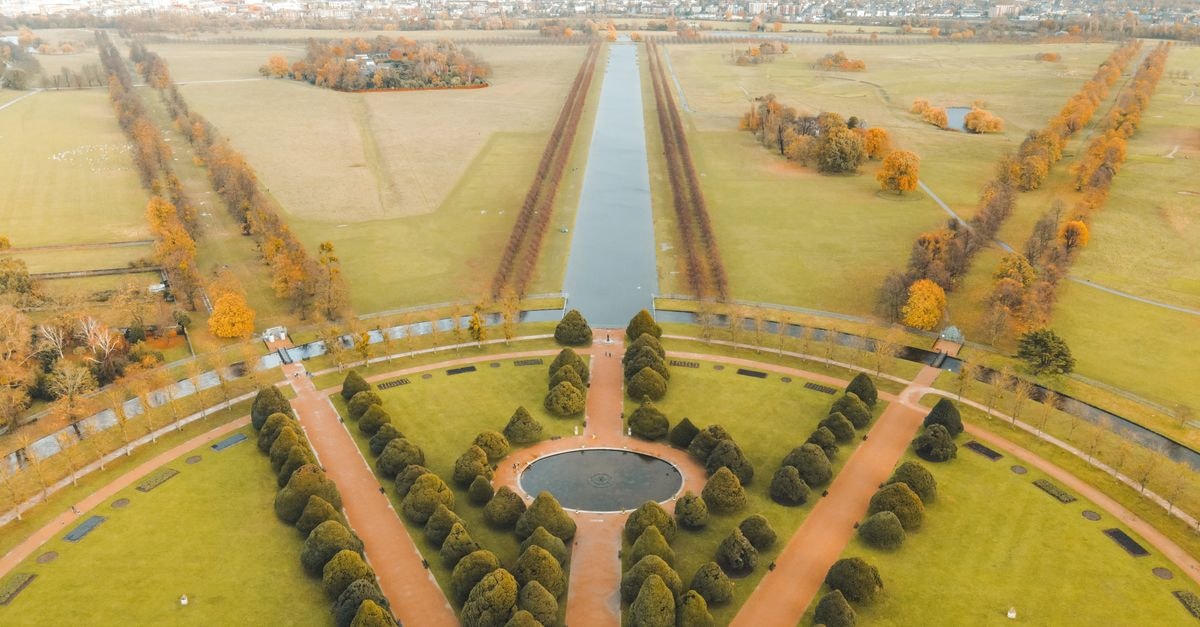 Surrey Travel Guide: Planning Tips, Costs and Things to Do Picturesque aerial view of well groomed gardens and fountains of ancient historic Hampton Court Palace located in London