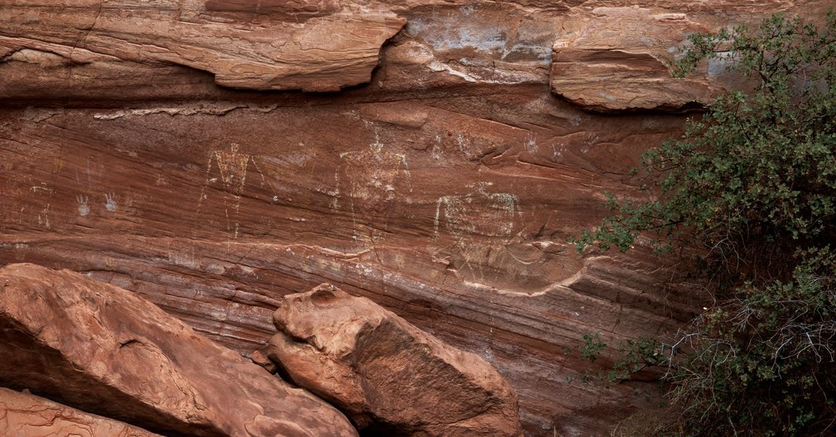 Explore ancient petroglyphs etched on red sandstone cliffs, showcasing historical art and culture in a natural landscape.