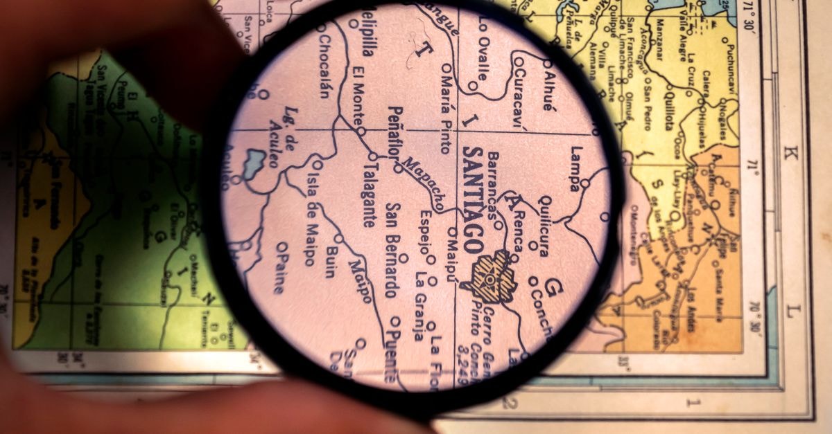 Close-up of a magnifying glass highlighting Santiago on a vintage map of Venezuela.