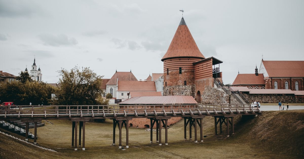 Kaunas Travel Guide: A Slow Stroll Through Lithuania's Second City View of the historic Kaunas Castle with its distinctive red brick towers and wooden bridge.