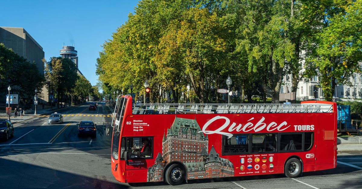 Biltine Travel Guide: Weather, Transport, and Planning Double-decker tour bus on a street in Quebec City, showcasing urban landscape and greenery.