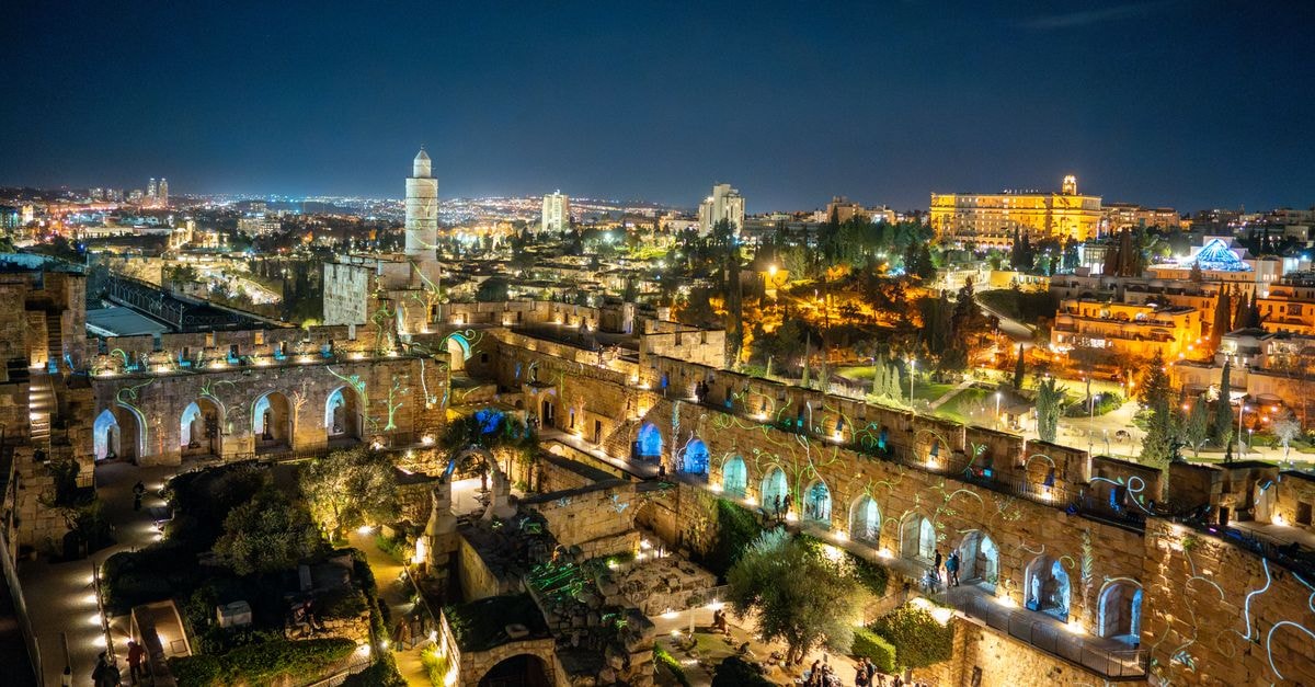 Waldorf Astoria Jerusalem: Heritage Facade Meets Modern Grandeur A stunning nighttime view of the illuminated Tower of David and Jerusalem cityscape, showcasing historical architecture.
