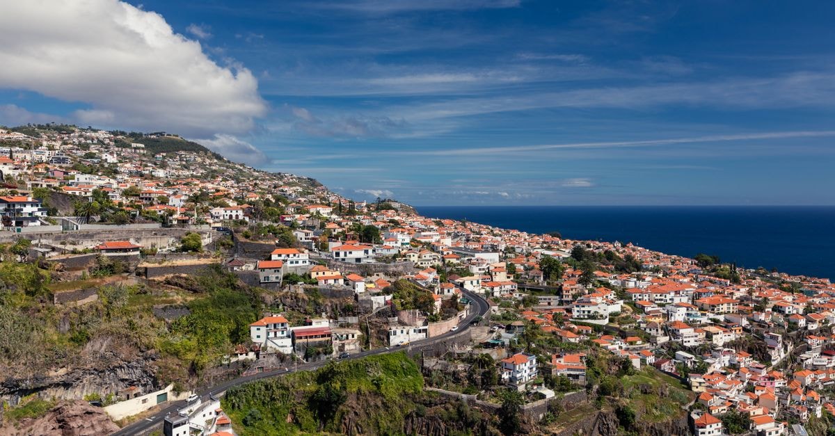 La Fora Ecolodge, São Filipe — Caldera-Slope Bungalows for Fogo Adventures A scenic aerial view of Funchal, Madeira with charming red-roofed houses under a bright blue sky.