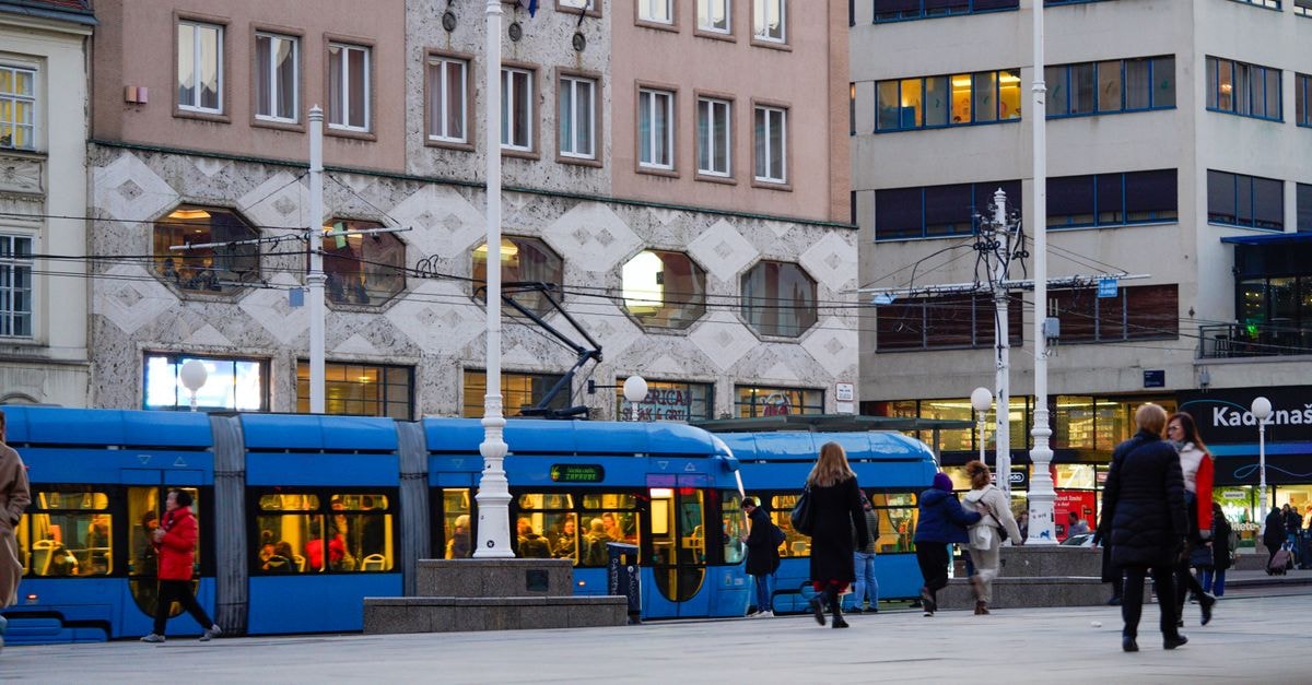 Dots Hostel Zagreb: A Lively Pocket Between Two Squares Vibrant street scene featuring a blue tram and pedestrians in Zagreb, Croatia.