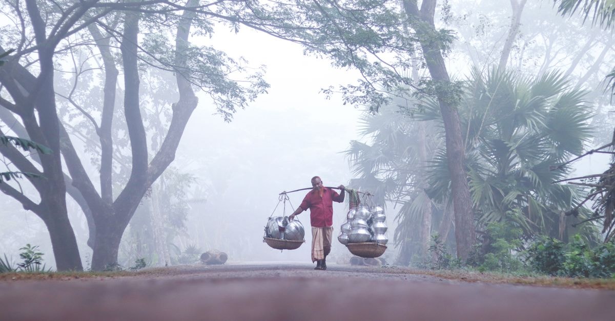 Slow Mornings in Kulti: A Bengal Travel Guide A man carries goods in a foggy village in Barisal, Bangladesh.