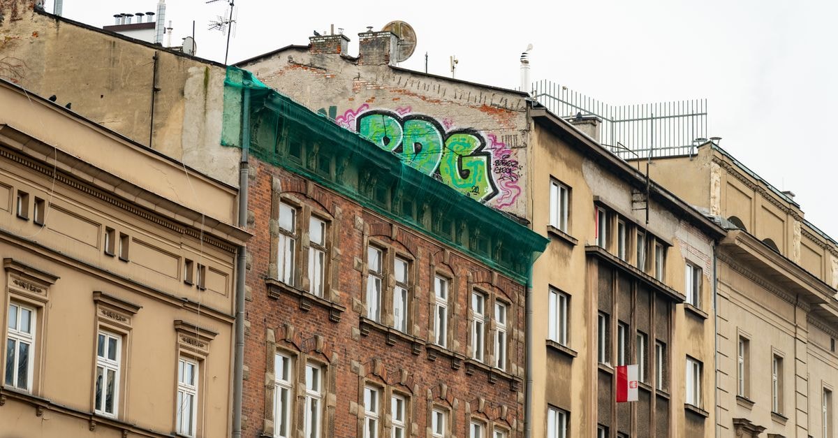 Colorful graffiti on historic buildings in Kraków, Poland, showcasing urban art contrasting old architecture.