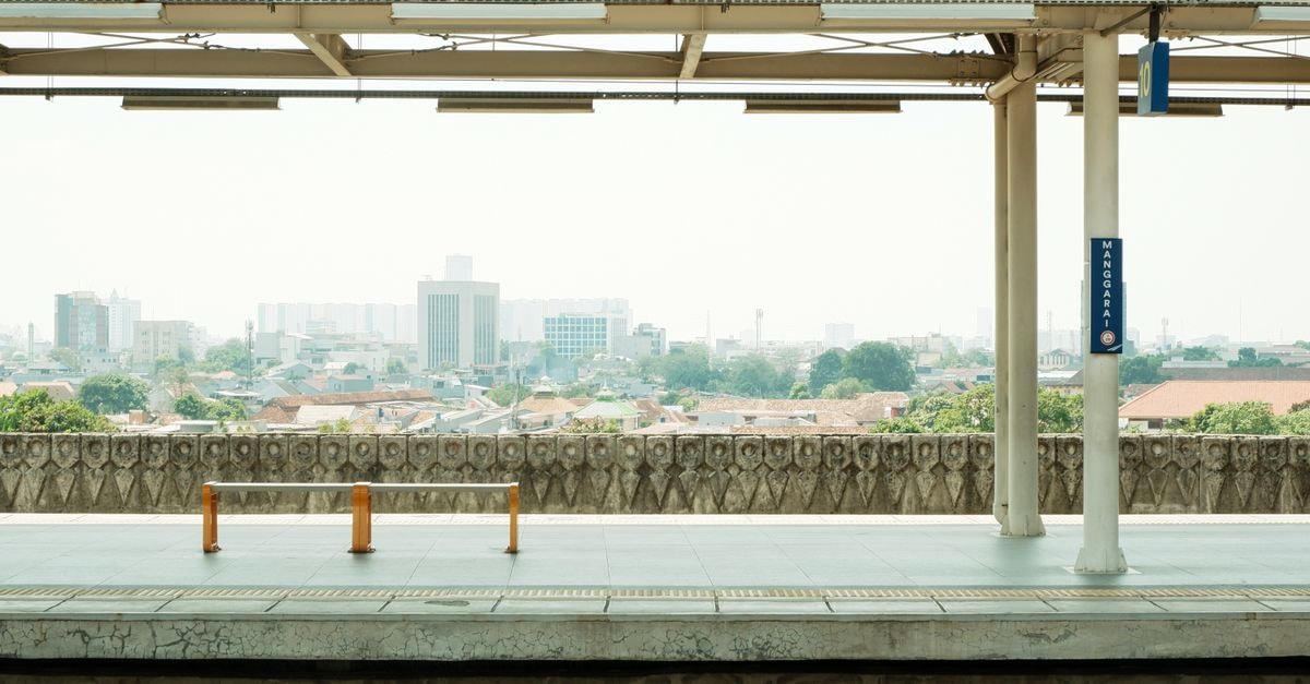 Jakarta Travel Guide: Planning Tips, Costs and Things to Do View of an empty train station platform in Jakarta, Indonesia with city skyline in the background.