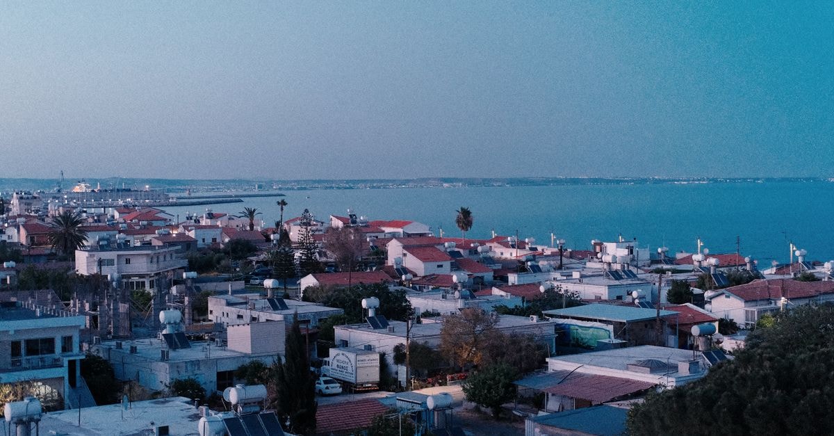 Jimmy’s Suites Larnaca: Style and Comfort in the Heart of Larnaca Aerial view of Larnaca's rooftops leading to a serene sea horizon at sunset.