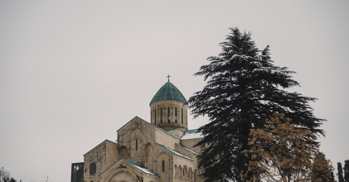 Telavi Travel Guide: Wine Country Calm Beyond Tbilisi A serene winter view of a historic cathedral in Tbilisi, Georgia with snow-covered trees.