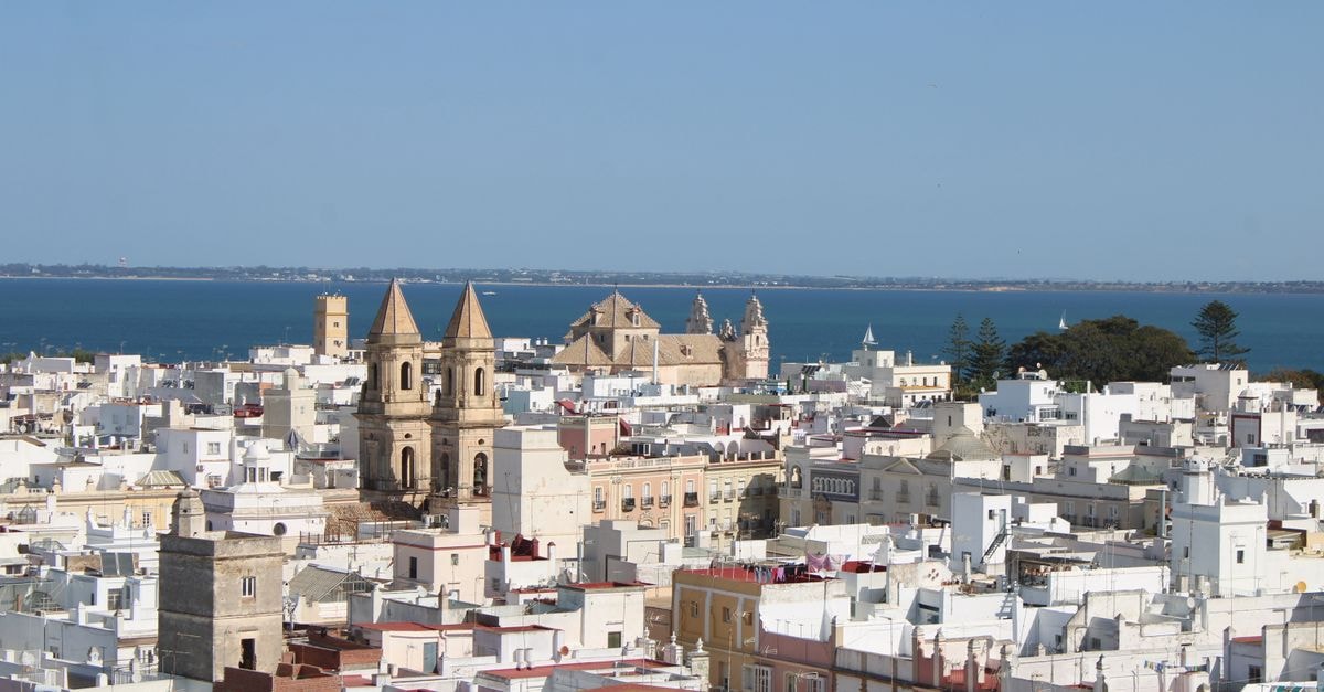 View of Cádiz's white buildings and Torre Tavira against the sea.