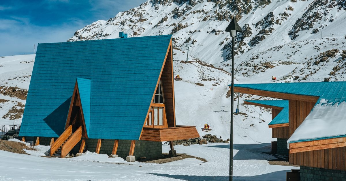 Cozy A-frame cabins nestled in a picturesque snow-covered mountainous landscape, perfect for a winter retreat.