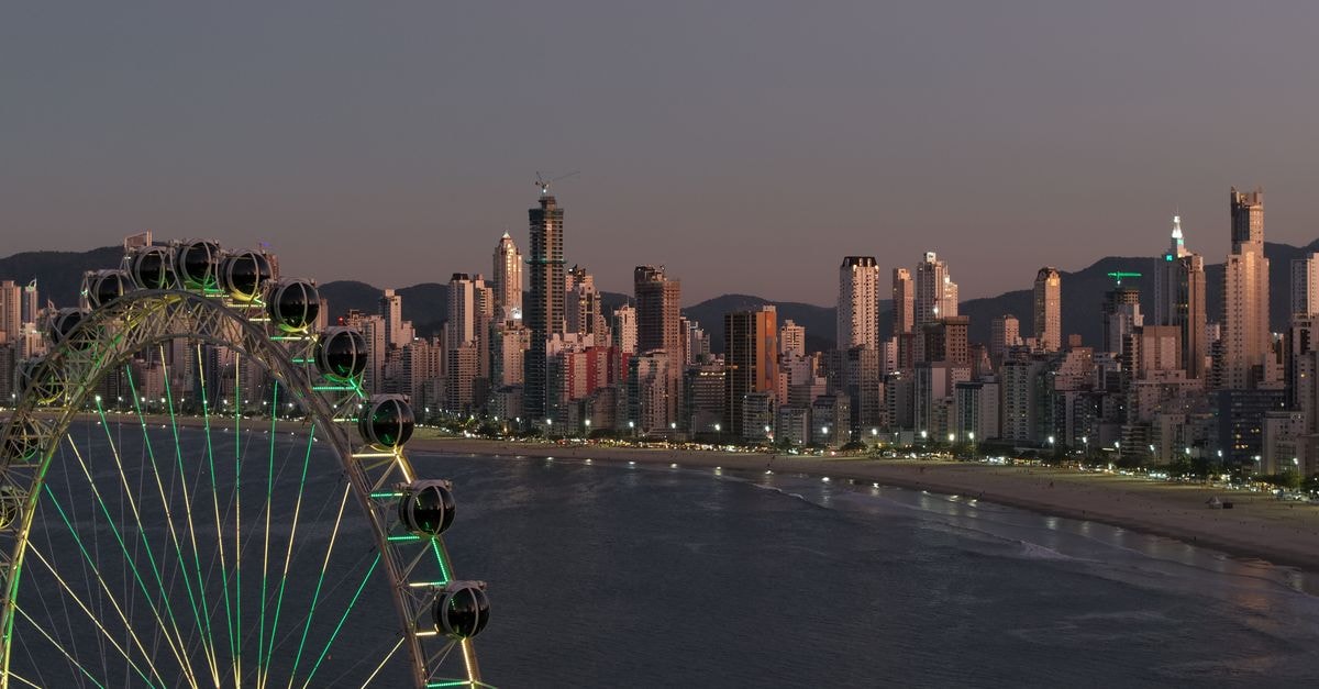 Spectacular skyline of Balneário Camboriú with an illuminated ferris wheel during twilight.
