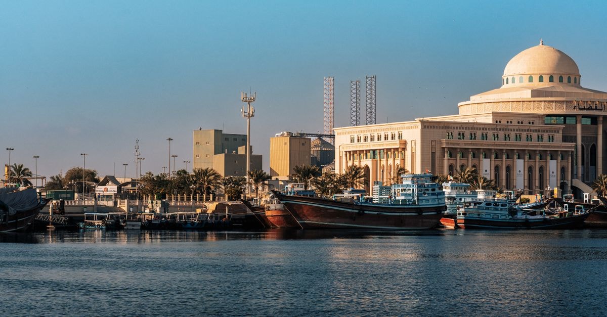 Dammam Travel Guide: Planning Tips, Costs and Things to Do A scenic view of Sharjah's iconic waterfront with boats and traditional buildings.