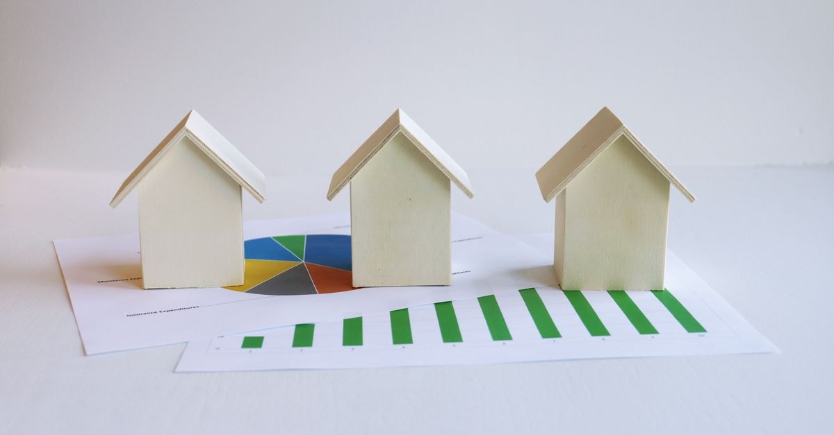 Newmark Group: Trading Below the Deterministic Range, but Earnings Quality Needs Watching Wooden model houses on graphs depict real estate market analysis and trends.