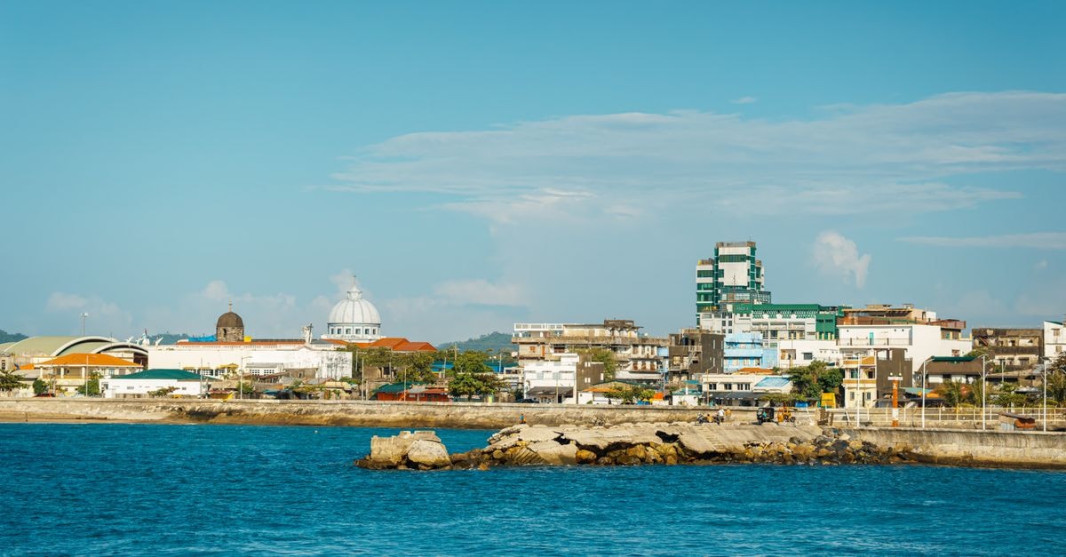 Panoramic view of a vibrant coastal cityscape with clear blue skies and ocean foreground.