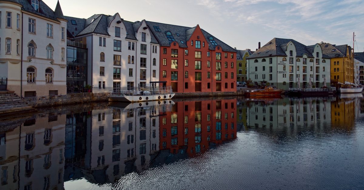 Thon Hotel Baronen in Ålesund: A Quiet Stay Near Moa Charming waterfront buildings in Ålesund, Norway with vibrant reflections in the calm sea.