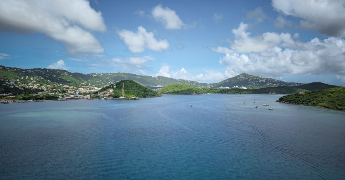 Water Island Villas in Charlotte Amalie: 3-Min Walk to Honeymoon Beach Breathtaking view of the Caribbean Sea with green hills and boats under a blue sky.